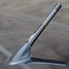 A black carbon fiber short radio antenna is shown angled against a dark surface.