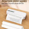 A white portable printer with roll paper and carbon ribbon supplies resting on a wooden surface.