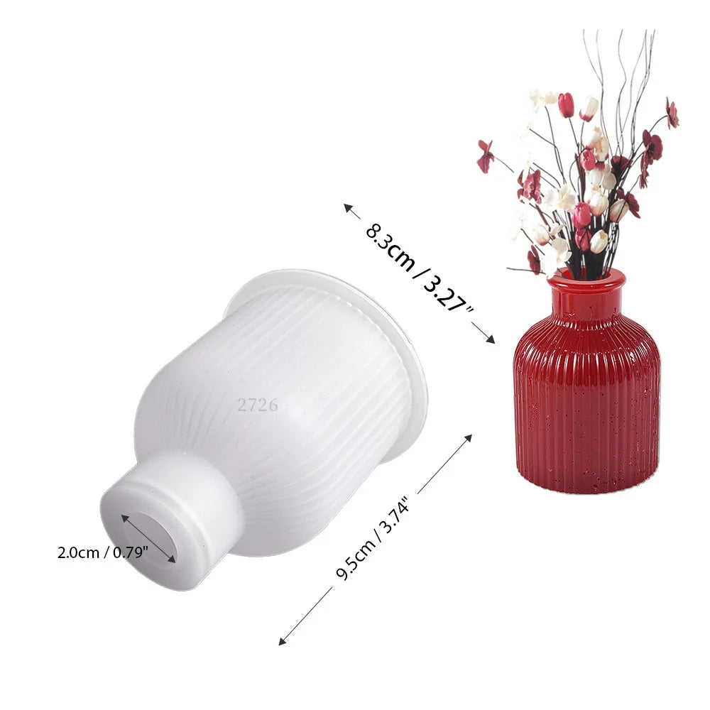 White silicone mold with a base and a round top, shown next to a red vase with dried flowers.