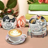 A set of diamond art coasters featuring cats and roses with a metal stand and a cup of latte.