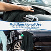 A hand is using a black microfiber car drying towel to clean the exterior of a car.