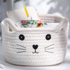 A white woven cotton rope storage basket shaped like a cat's face with black features.