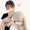 A person is holding a light brown long-eared rabbit plush toy against their chest.