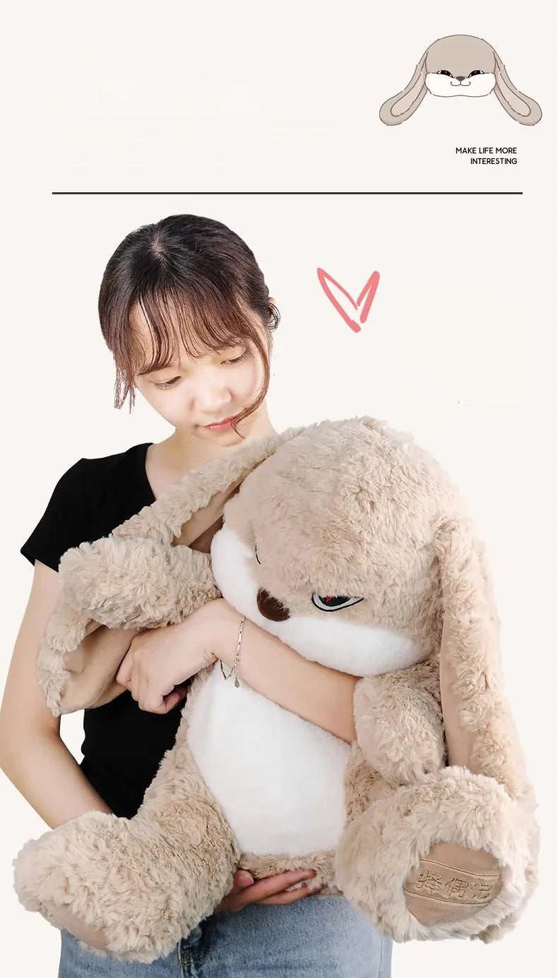A person is holding a light brown long-eared rabbit plush toy against their chest.
