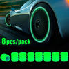 Eight luminous green glow-in-the-dark tire valve caps displayed on a dark background.