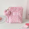 A pink faux fur cosmetic bag with a leopard print texture and a pink pom-pom charm.