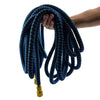 A hand is holding a coiled blue expandable garden hose with a brass nozzle.