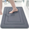 A gray absorbent soft non-slip bath mat is shown with a bare foot resting on it in a bright bathroom setting.