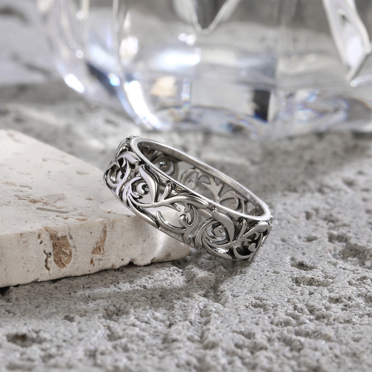 Bague en argent sterling vintage creuse florale posée sur une surface texturée gris clair.