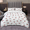 White duvet cover set with a red cherry print and matching pillowcases displayed on a bed.