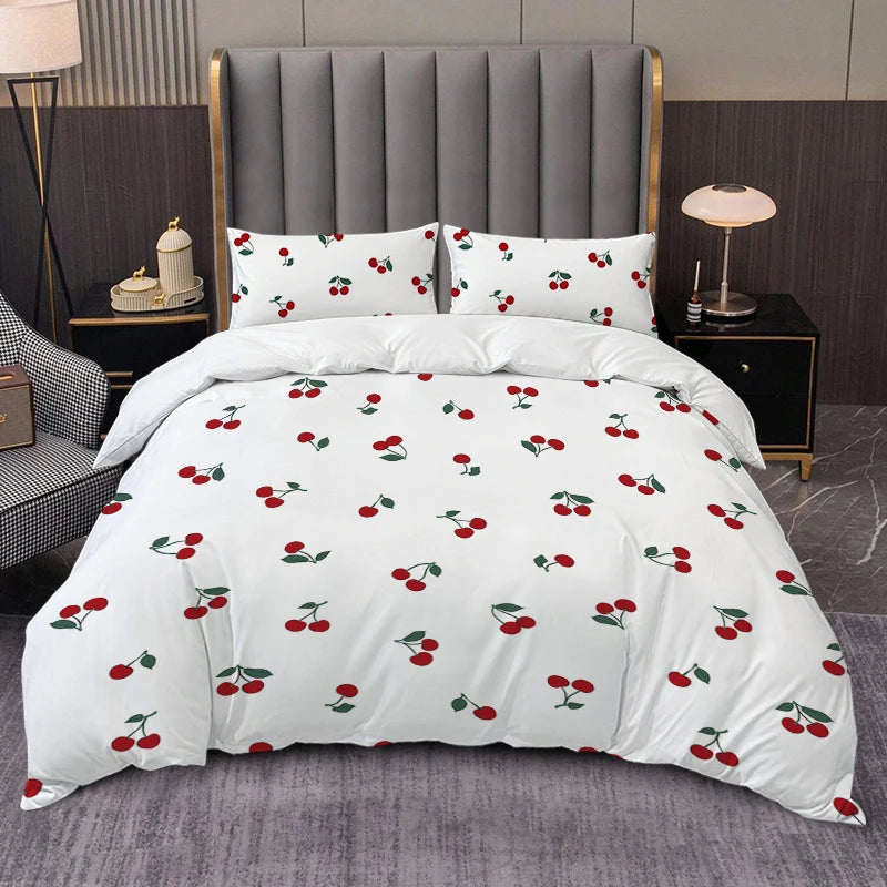 White duvet cover set with a red cherry print and matching pillowcases displayed on a bed.