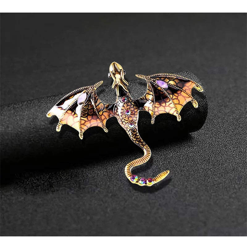 A detailed enamel dragon brooch featuring iridescent scales and rhinestone accents on a black background.