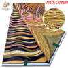 A close-up view of a yellow and orange African wax print fabric with swirling patterns.