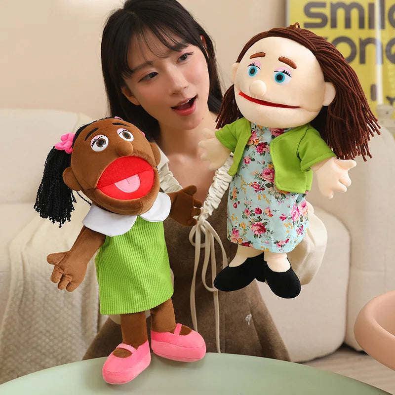 A soft plush full-body hand puppet resembling a child with brown skin and dark hair, dressed in green clothing.