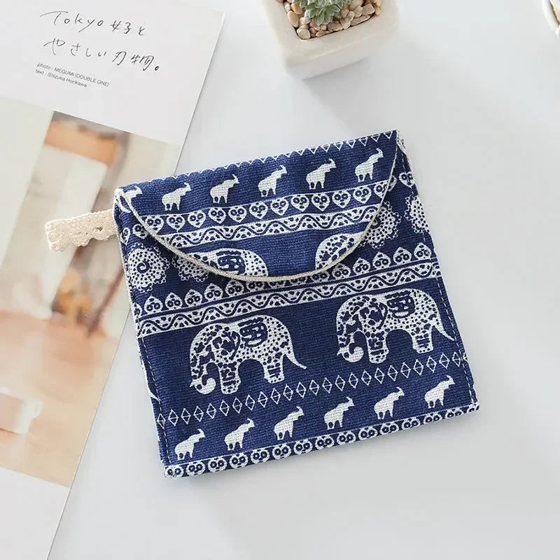 A navy blue cosmetic storage pouch featuring white elephant patterns and a light beige fabric tag.