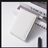 A white slim vertical leather wallet with a stitched edge is shown resting on a white surface next to a black pen.