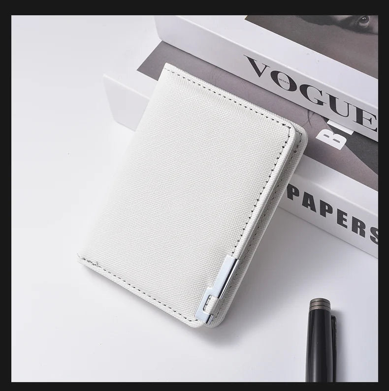 A white slim vertical leather wallet with a stitched edge is shown resting on a white surface next to a black pen.