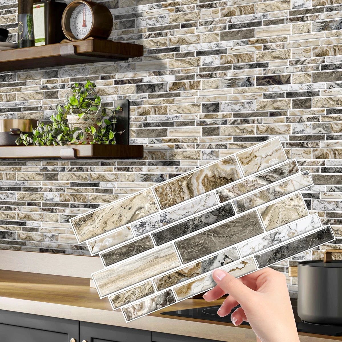 A hand is placing peel and stick waterproof tile stickers on a kitchen backsplash made of stacked marble-look tiles.