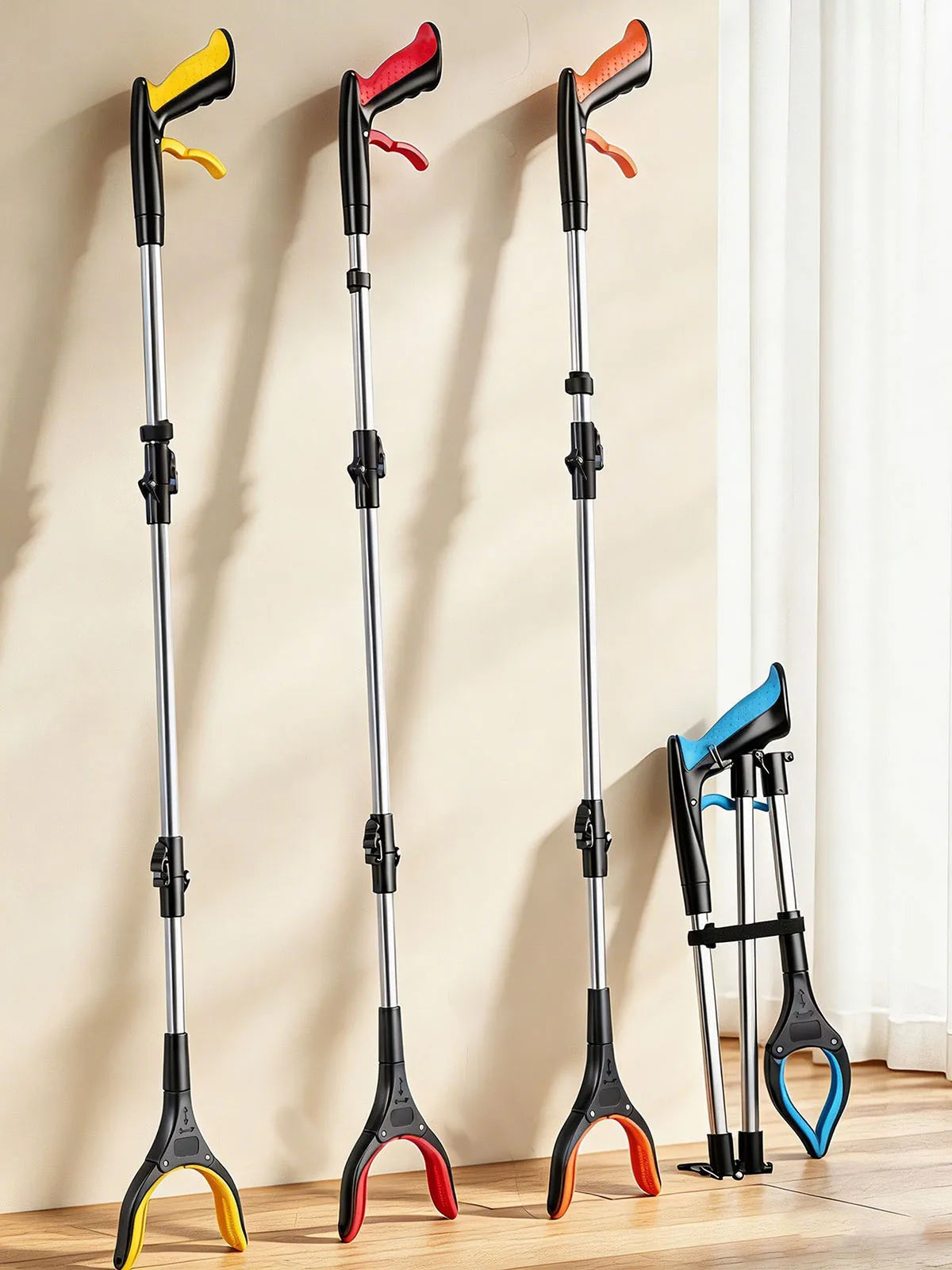 Three black and orange foldable grabber reachers displayed vertically against a light wall.