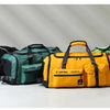 Four tactical nylon backpacks in black, green, and yellow are displayed on a white surface.