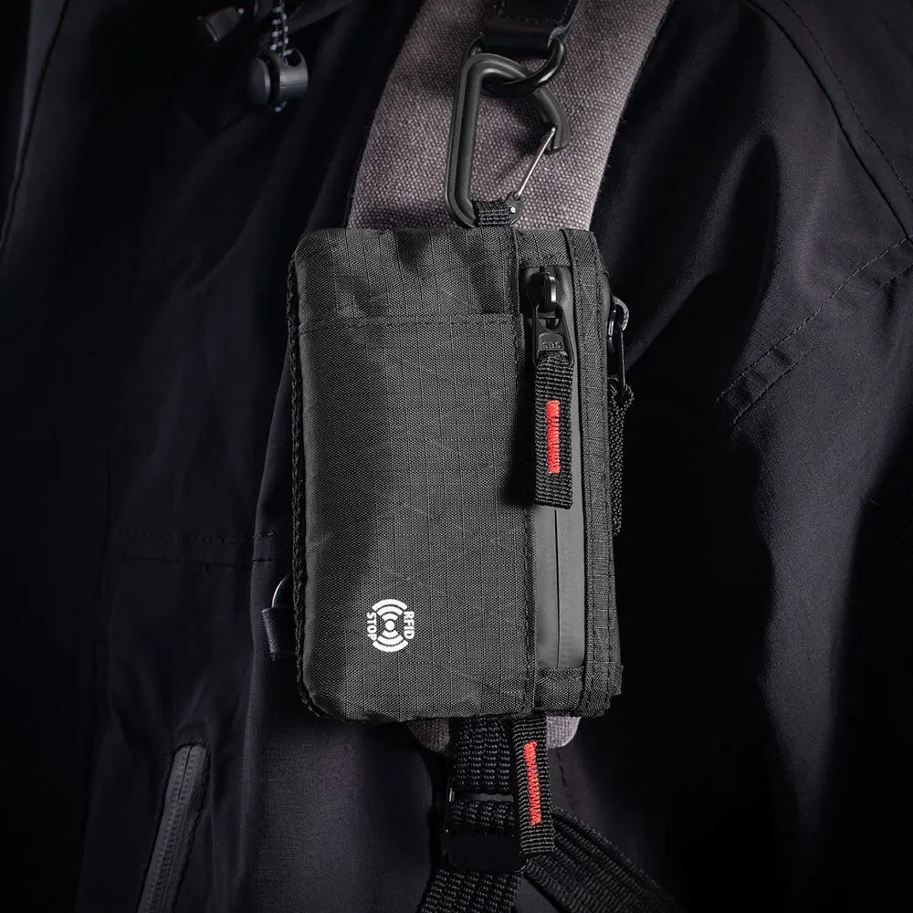 Black RFID-blocking travel wallet attached to a jacket with a carabiner clip.