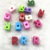 A collection of 10 mixed alphabet letter beads in various colors including pink, green, purple, and red.