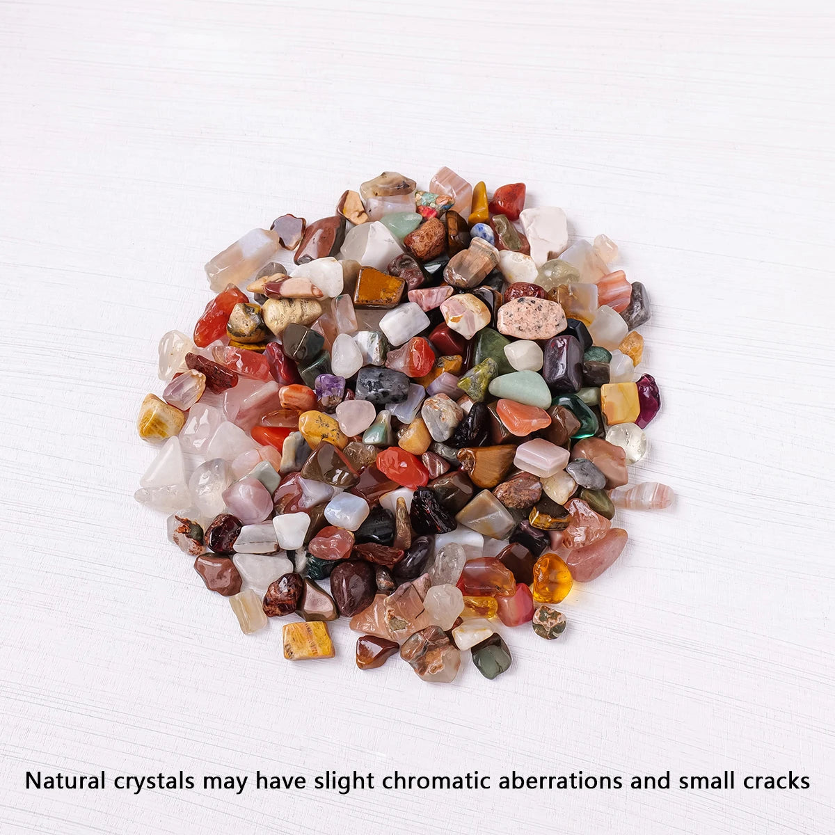 A pile of mixed natural crystal gravel stones showing various colors including pinks, reds, greens, and browns.