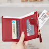 A red PU leather bifold wallet with a gold zipper and an ID card visible inside, held by a hand.