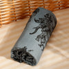 A gray muslin baby swaddle blanket featuring a black and white illustration of various animals.