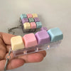 A hand holds a clear plastic keychain containing colorful mini mechanical keyboard fidget cubes for stress relief.