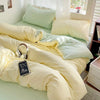 A yellow and mint green cotton bedding set featuring a flat sheet, duvet cover, and pillowcases on a bed.