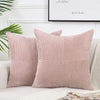 A set of two pink corduroy patchwork throw pillow covers with vertical ribbing on a white sofa.