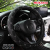 Close-up of a black embroidered leather steering wheel cover installed in a car interior.
