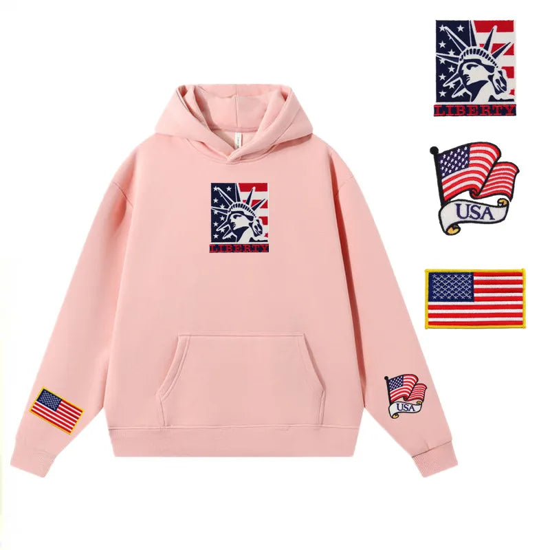 Light pink hoodie featuring embroidered American flag patches and USA emblems on the chest, sleeves, and pocket.