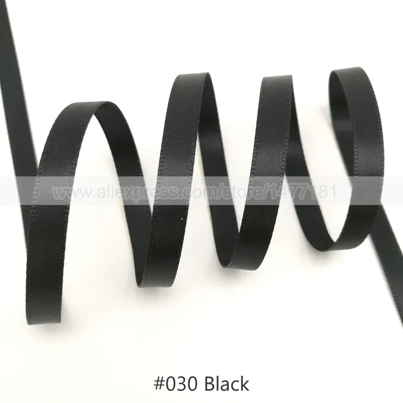 Black satin ribbon coiled and laid out against a white background
