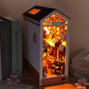 A miniature DIY book nook kit featuring a lighted wooden bookshelf room scene with an attic roof.