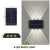 A black solar powered wall light with six LED white lights casting illumination upwards and downwards on a gray textured wall