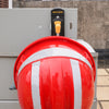 A red hard hat is mounted on a gray panel, featuring a black safety device with an orange trigger.