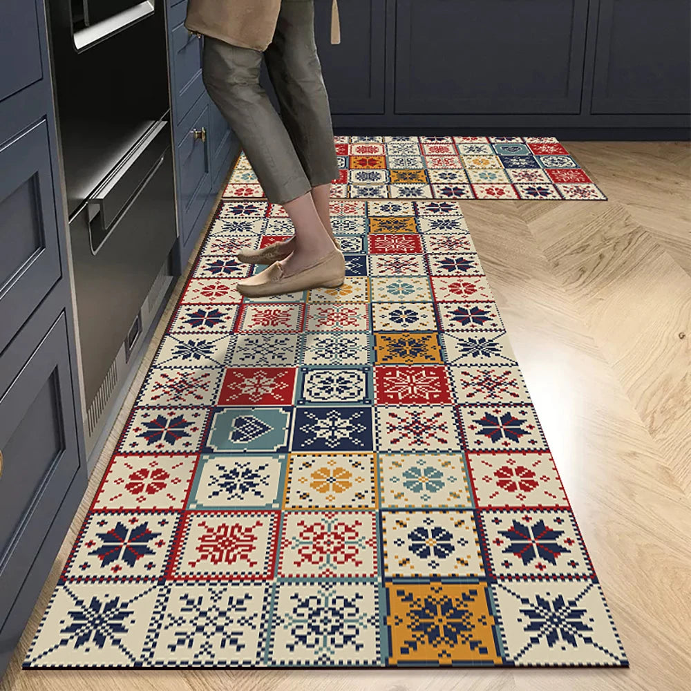 A rectangular floor mat featuring a geometric pattern in shades of blue, red, orange, and cream placed on a light wood floor.