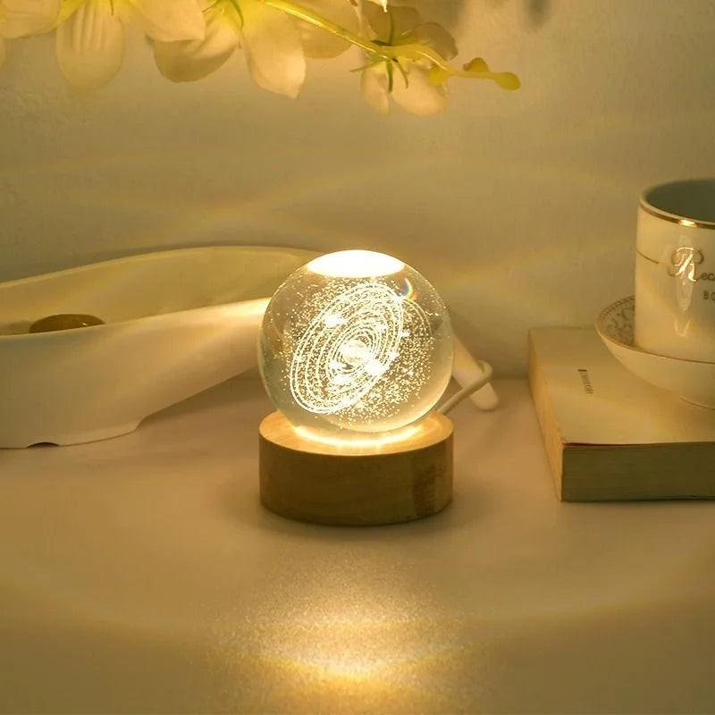 A laser engraved crystal ball night light rests on a wooden base, casting a warm glow.