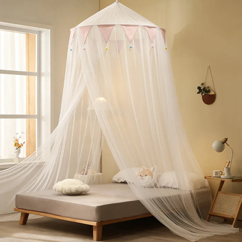 A sheer white romantic canopy mosquito net draped over a bed in a bright room.