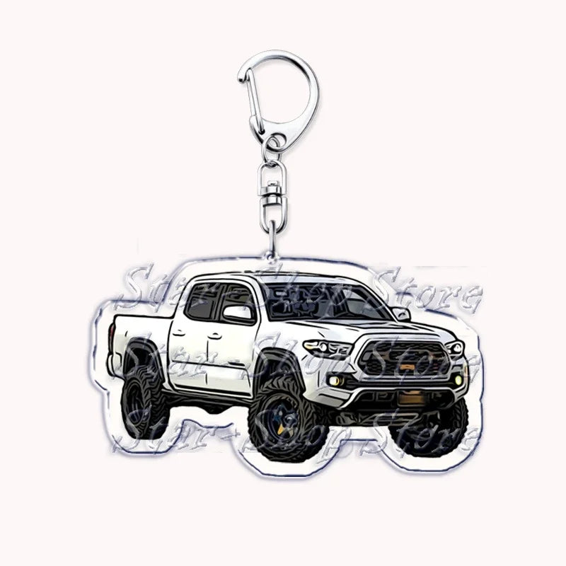 A silver metal key ring attached to a miniature model of a white off-road pickup truck.