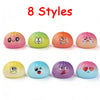 Huit jouets anti-stress colorés et moelleux dans diverses expressions et couleurs, disposés en rangée.