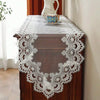 A dark wood cabinet with a white lace table runner and a small decorative plate on top.