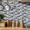 A kitchen backsplash featuring black and white marble tile stickers mounted on a gray subway tile wall.