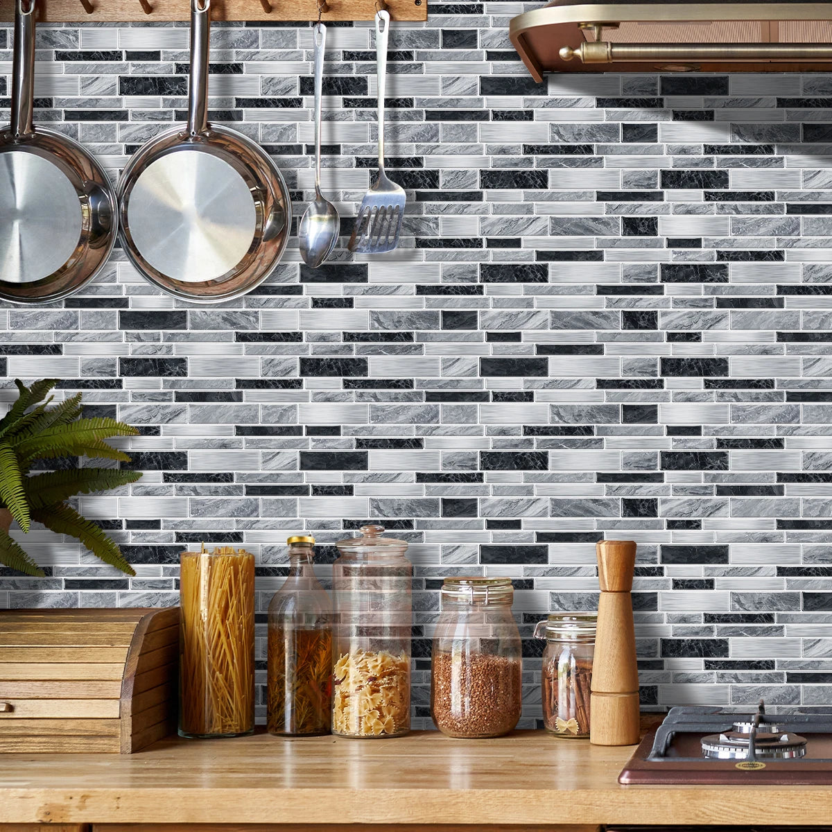 A kitchen backsplash featuring black and white marble tile stickers mounted on a gray subway tile wall.