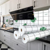 A kitchen featuring a black range hood and white subway tile splashback with green tropical leaves.