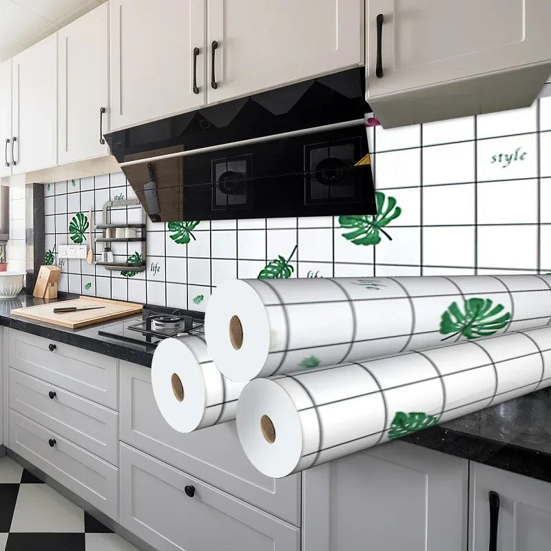 A kitchen featuring a black range hood and white subway tile splashback with green tropical leaves.