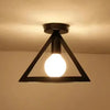 A black metal frame ceiling lamp with a single glowing light bulb.