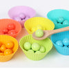 Colorful plastic muffin cups filled with wooden beads and a wooden spoon for a Montessori bead maze puzzle